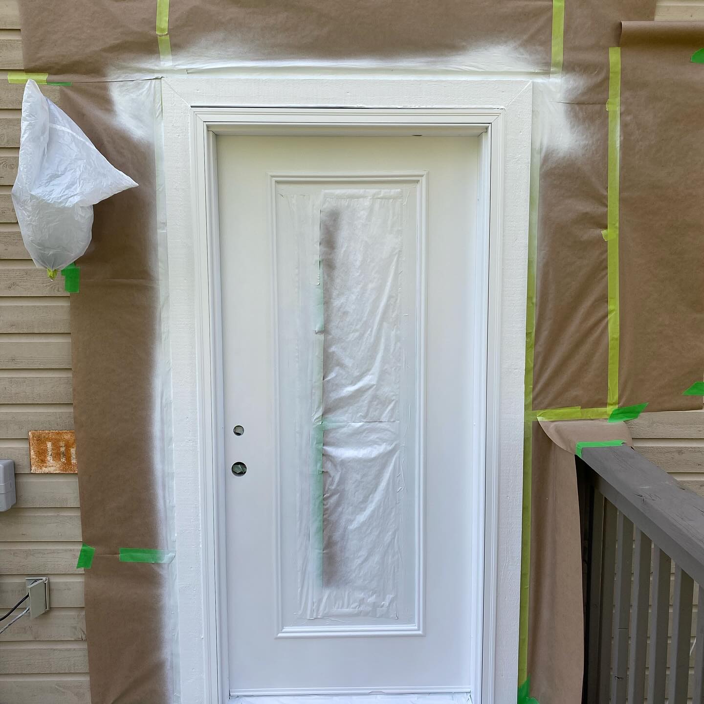 Front door masked off and primed with painter's tape and paper around the frame