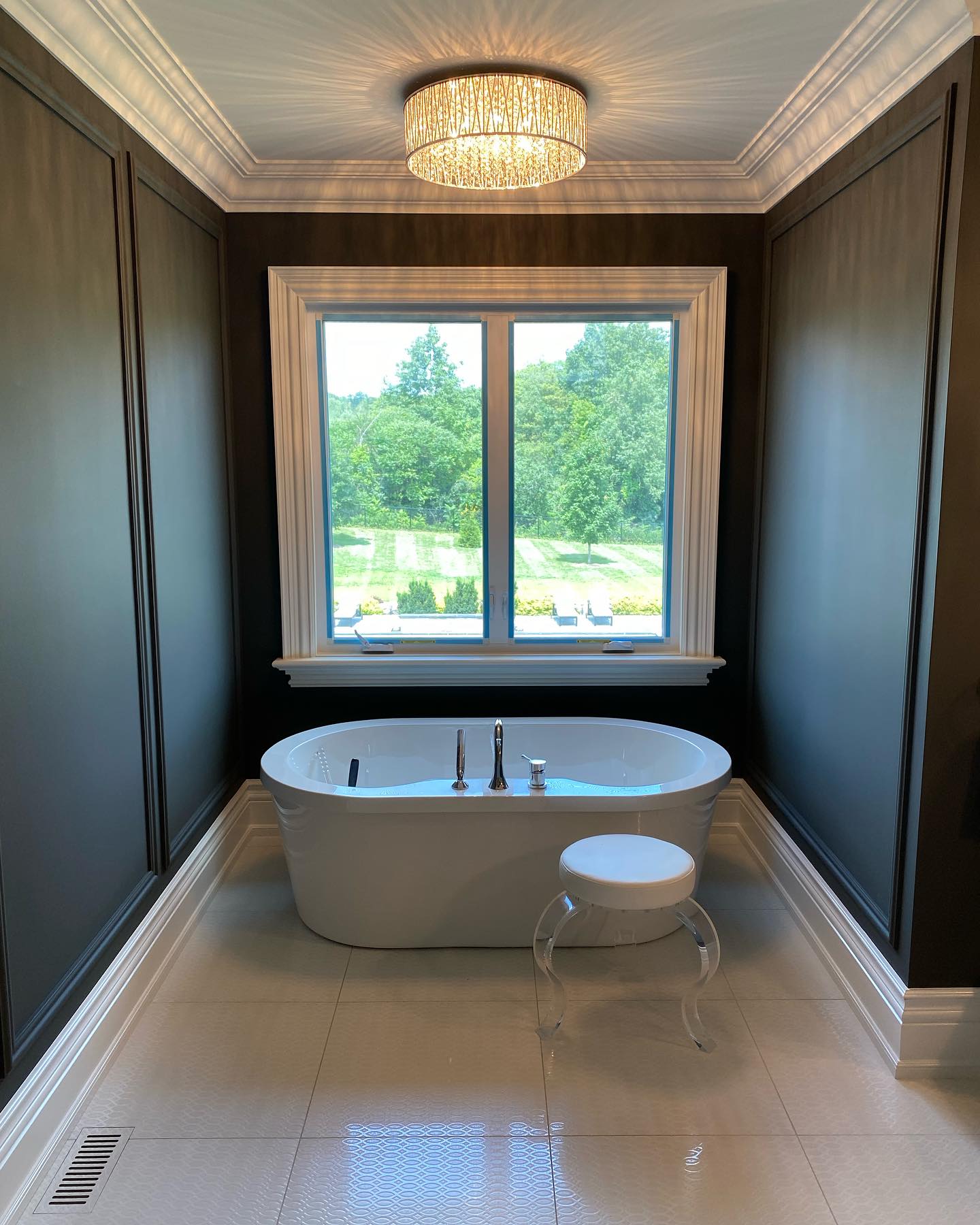 Bathroom with dark painted panelling, white freestanding tub and crown moulding
