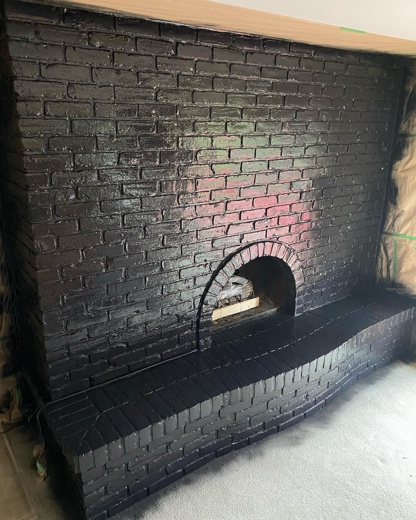 Large brick fireplace painted black with the hearth still being finished