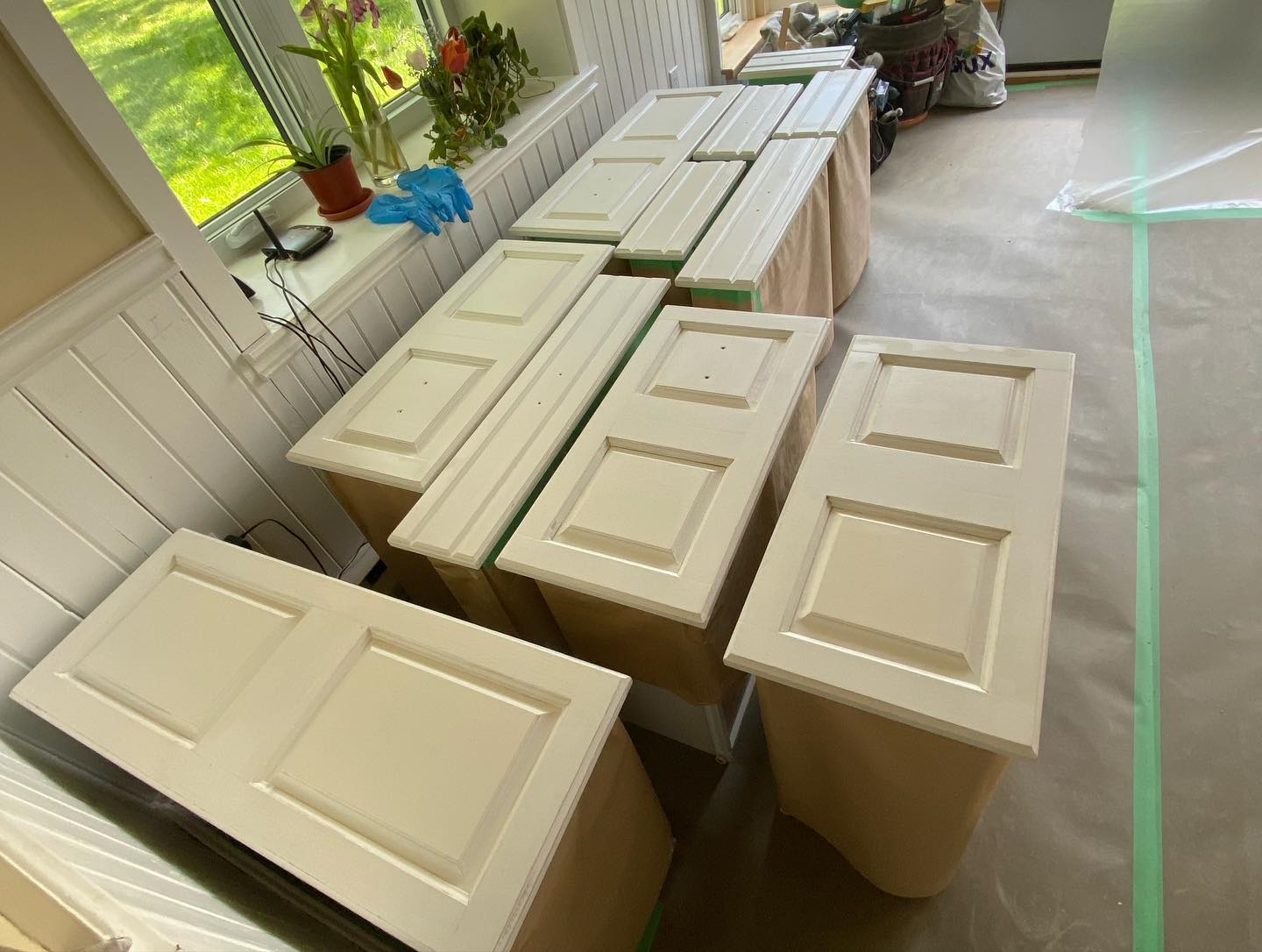 Painted cabinet doors laid out to dry on a protected floor
