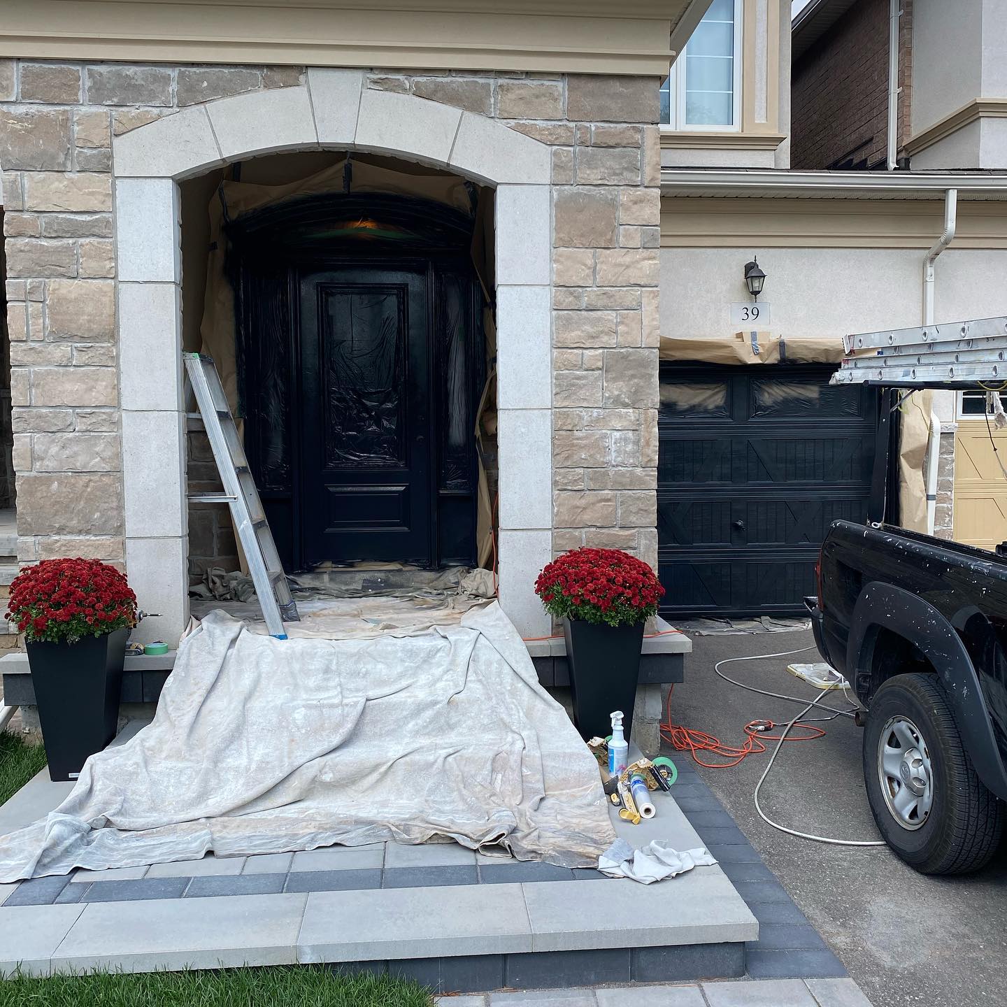 Black painted front door with stone arch surround and entry masked