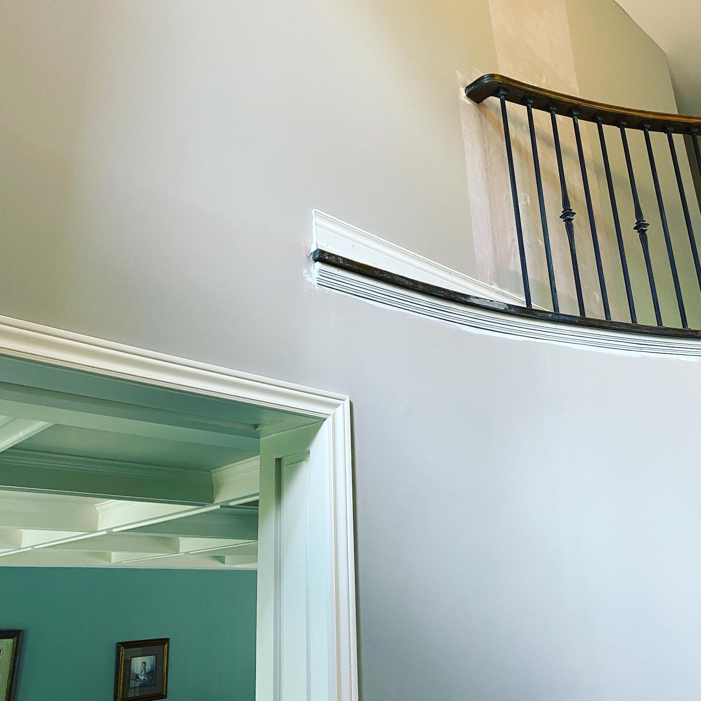 Curved stair rail with black iron spindles and freshly painted wall and trim
