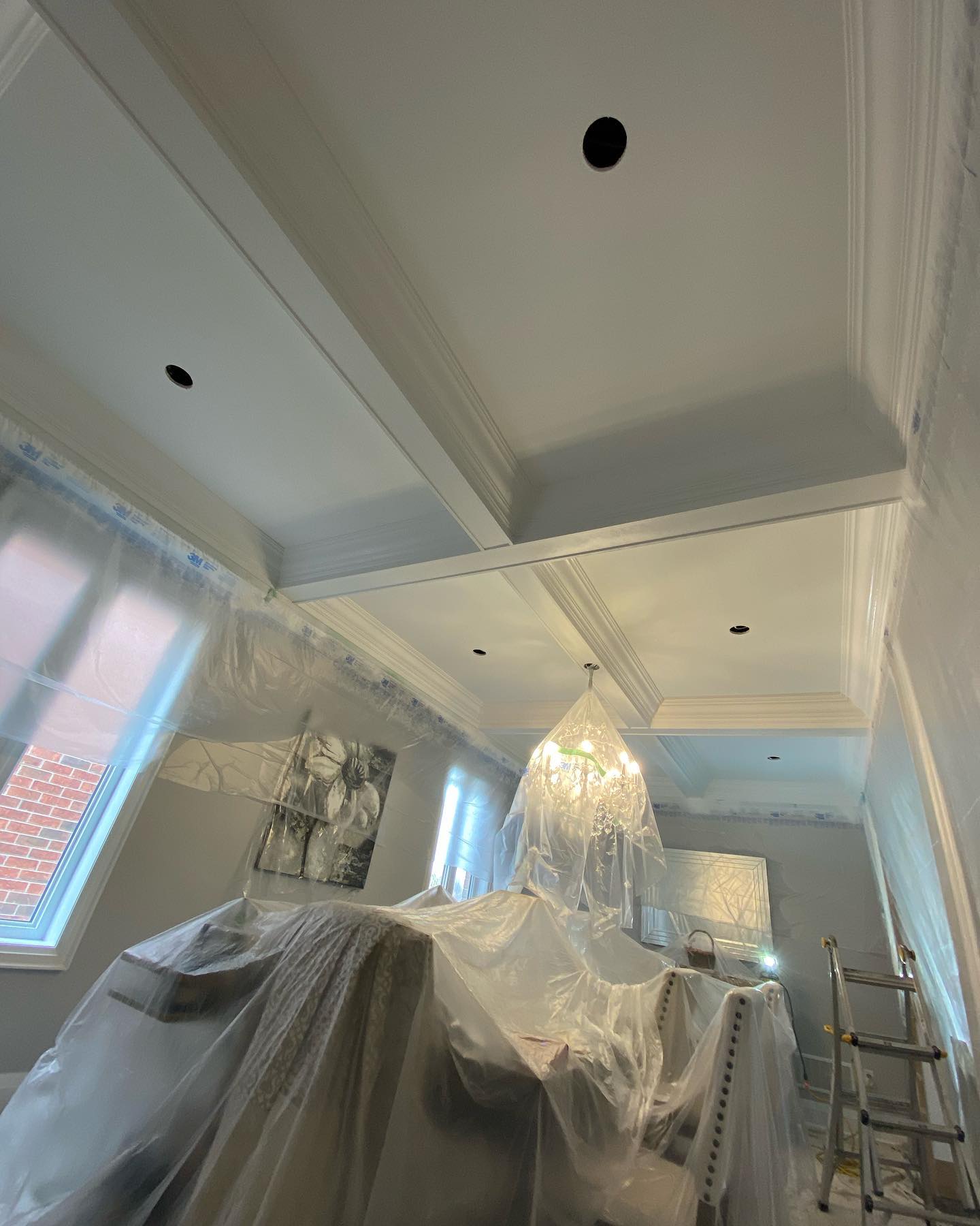 Freshly painted white coffered ceiling with the room wrapped in plastic