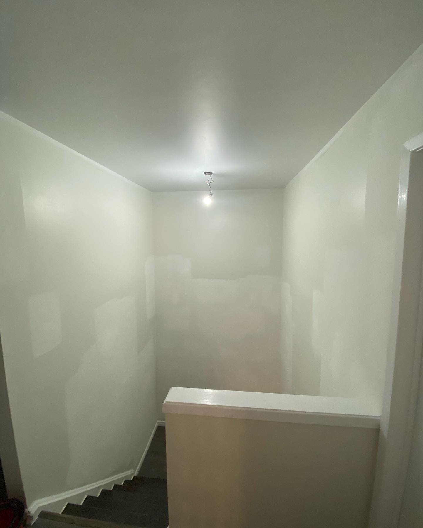 Stairwell with freshly patched and primed drywall walls and ceiling