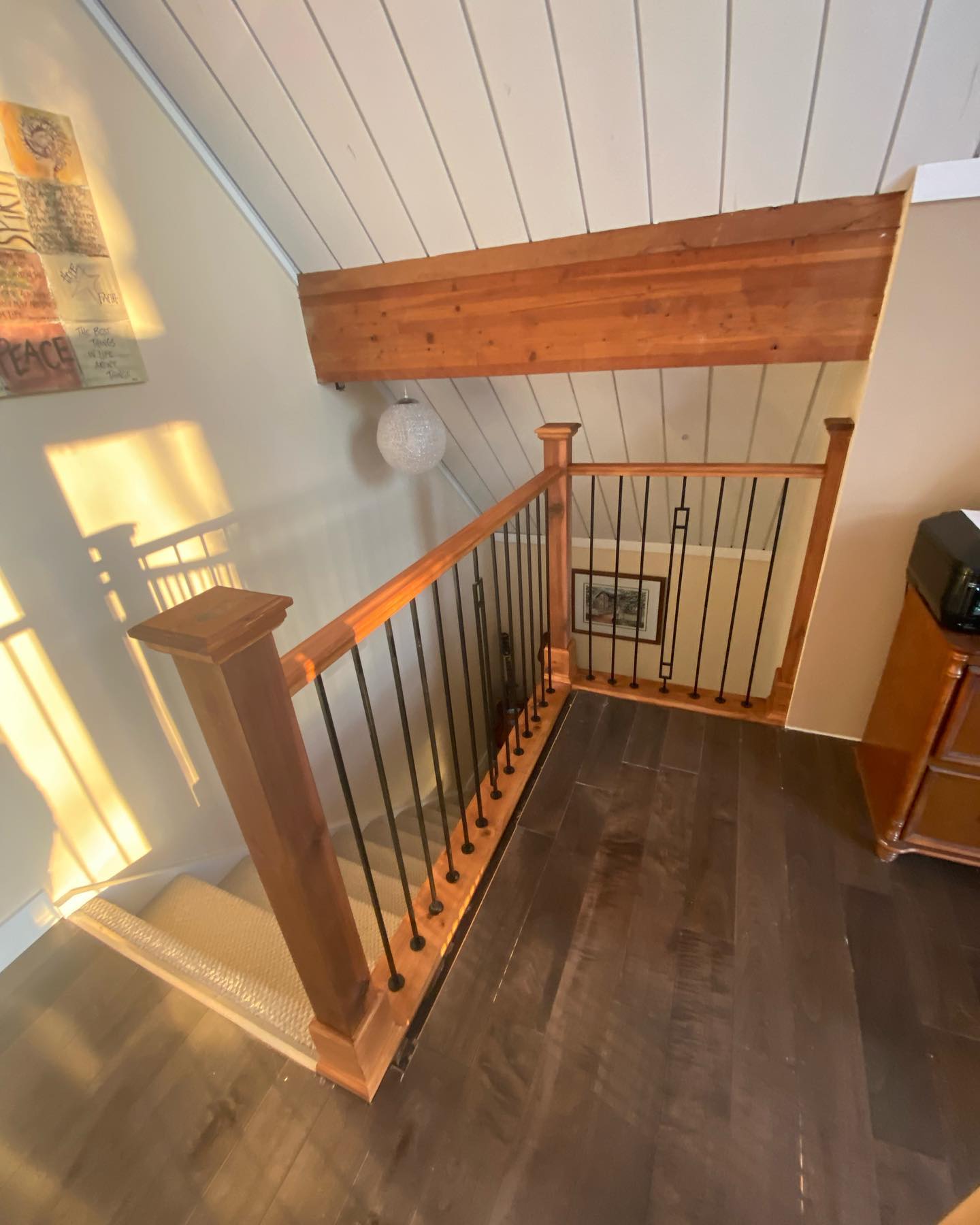Loft railing with wood handrail and white painted shiplap ceiling
