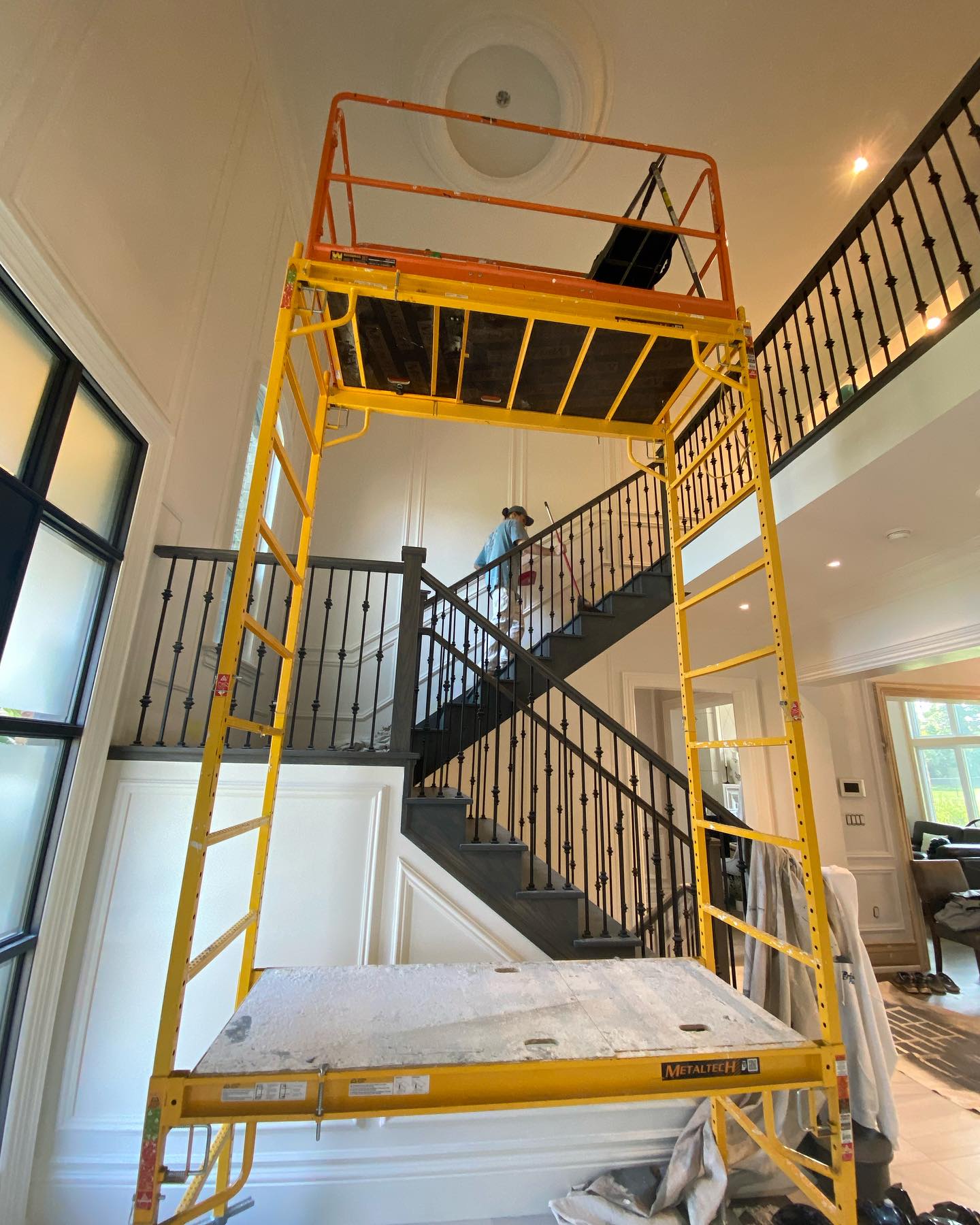 Scaffolding set up inside a tall open stairwell with a black metal railing