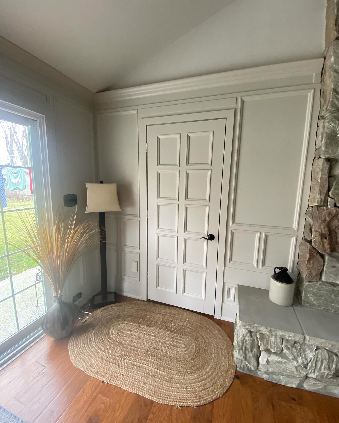 White panelled interior door and wainscoting beside a stone fireplace
