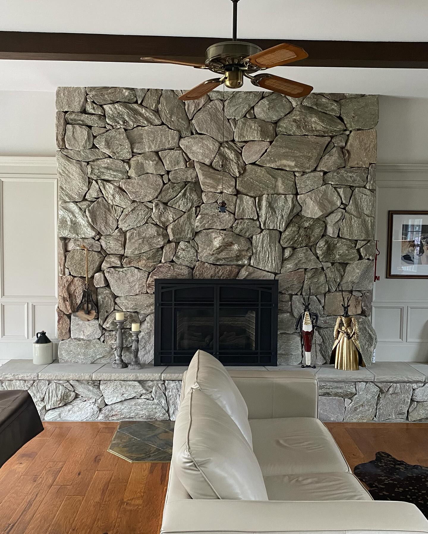 Stone fireplace in a living room with freshly painted walls and a wooden beam