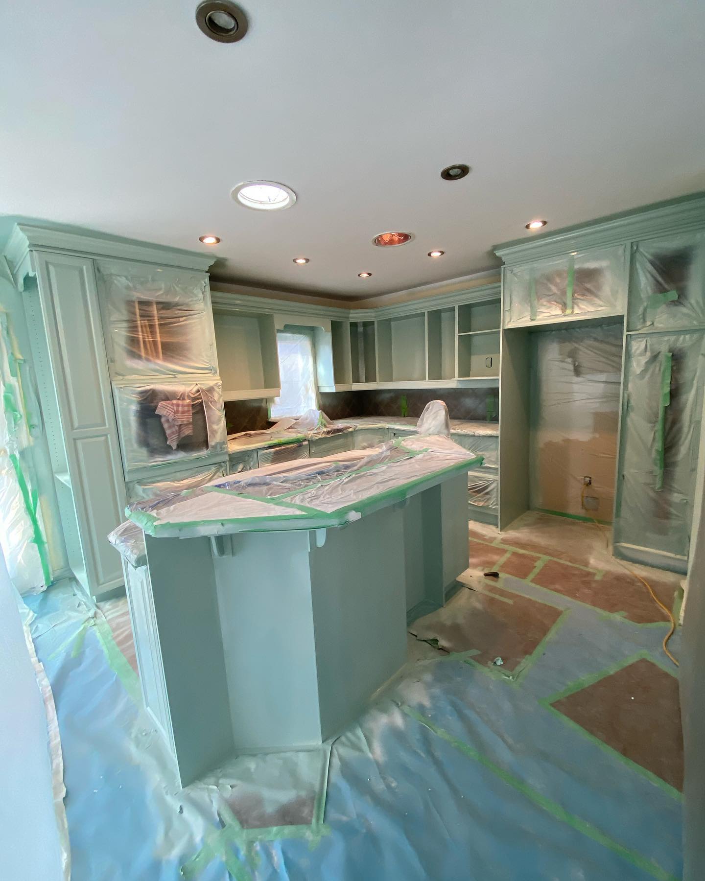 Kitchen being masked with paper and tape during cabinet painting