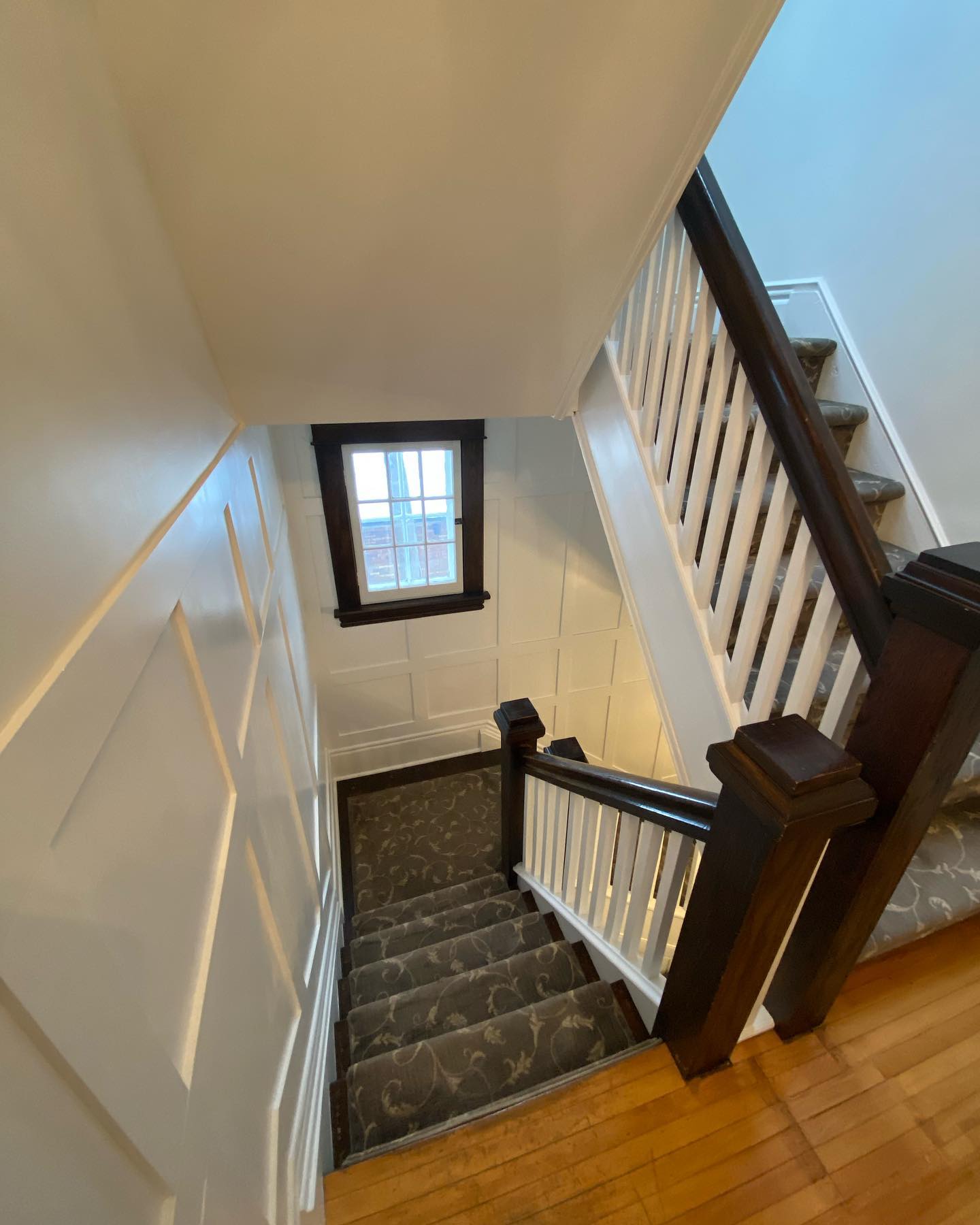 Stairwell looking down past a white painted railing and panelled wall