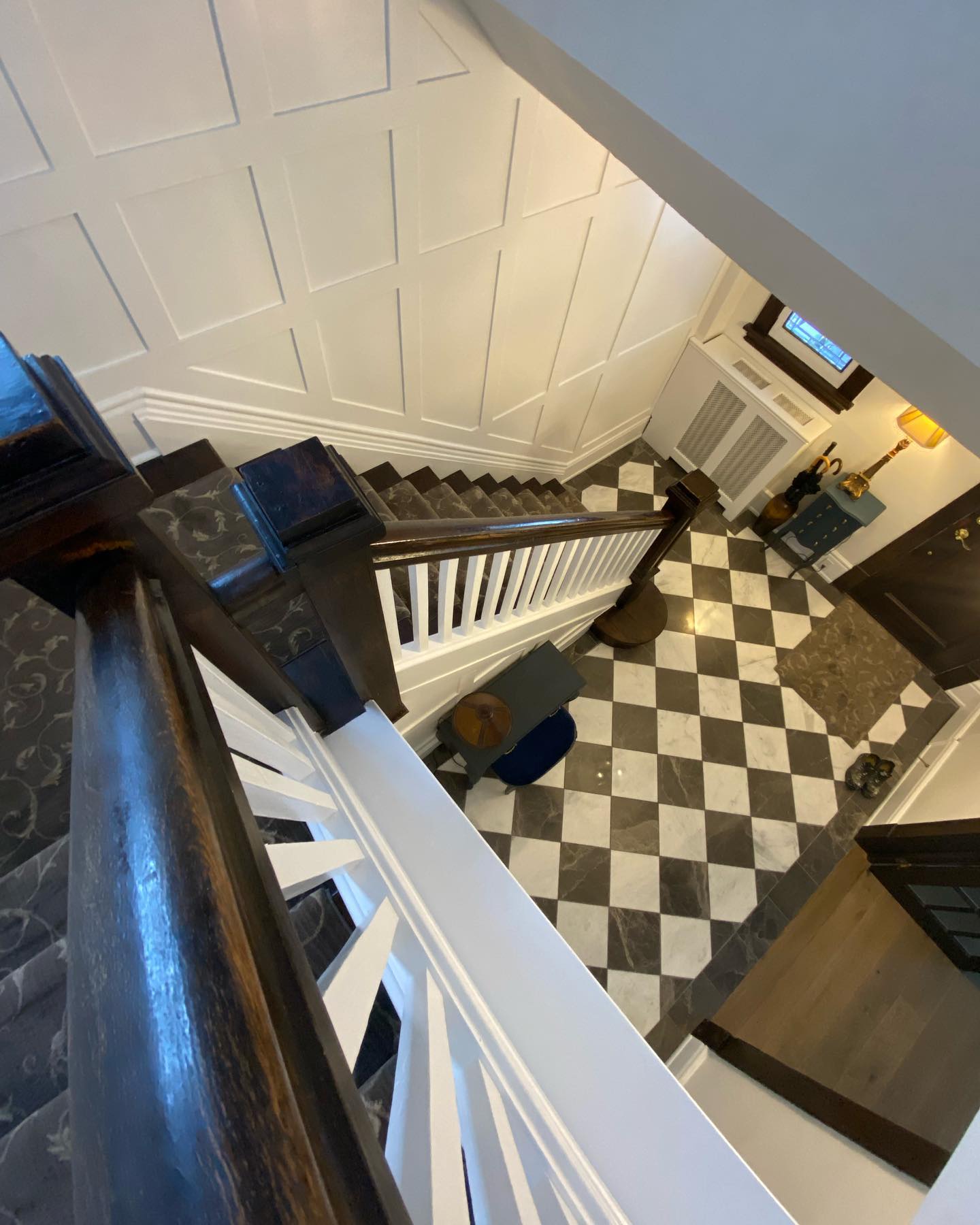 Open stairwell and checkerboard foyer floor seen from the upper landing